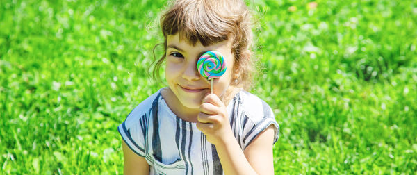 Portrait of girl holding lollipop in front of eye