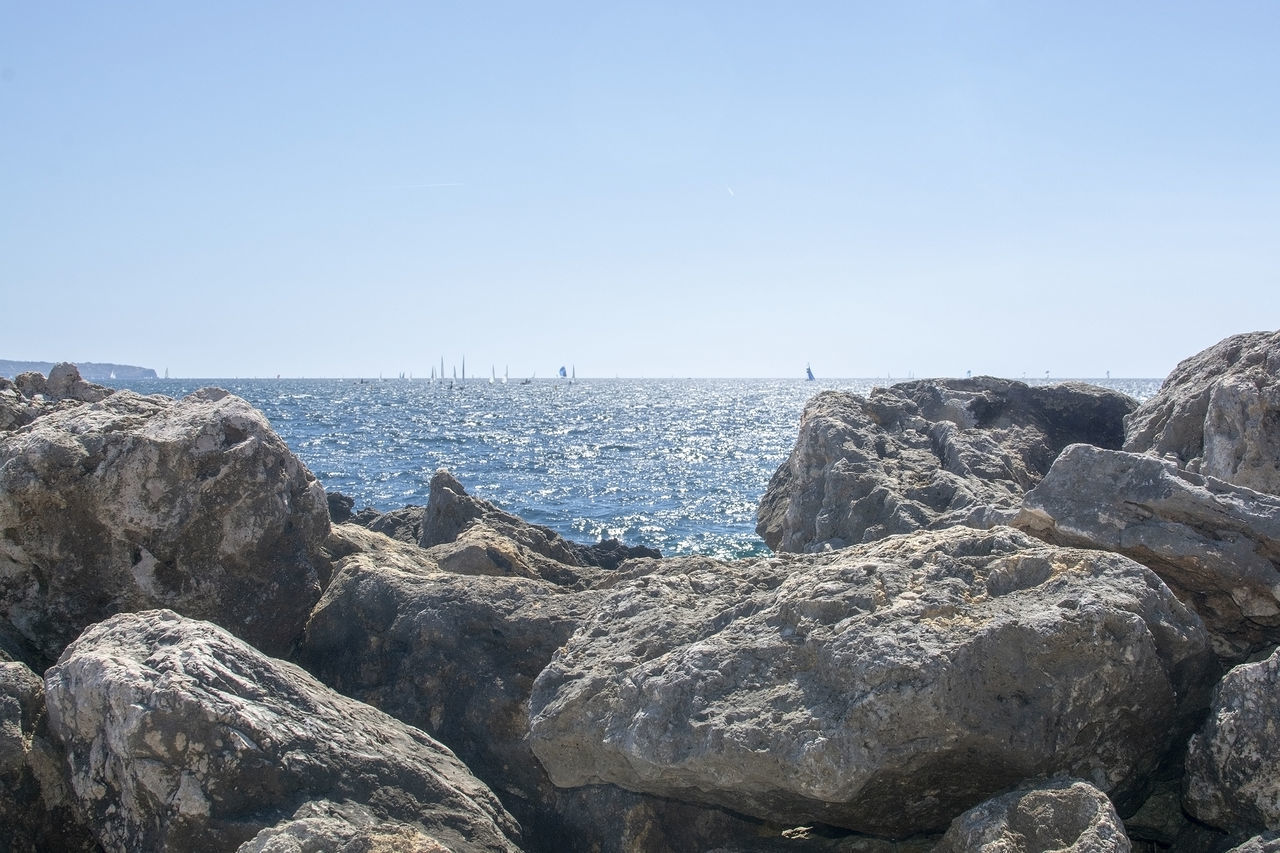 SCENIC VIEW OF ROCKS BY SEA AGAINST CLEAR SKY