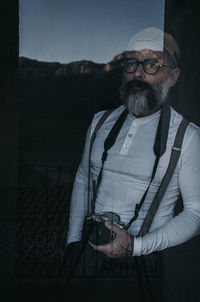 A man with camera in hand from a window in the mountains