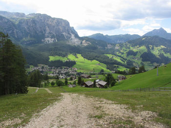 Alpine landscape with la villa village, green pastures and firs against italian dolomites at summer