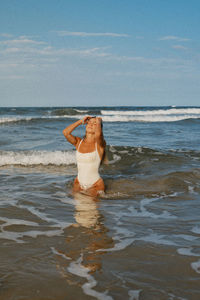 Rear view of woman standing in sea against sky