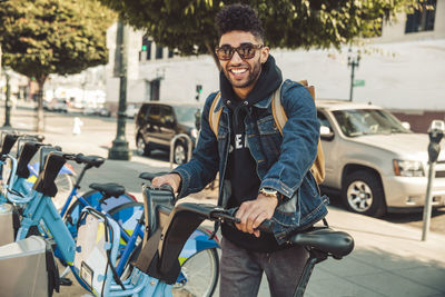 Stylish young man on the street with rental bike