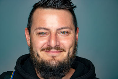 Close-up portrait of smiling man against blue background
