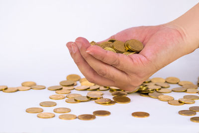 Close-up of hand holding coins over white background