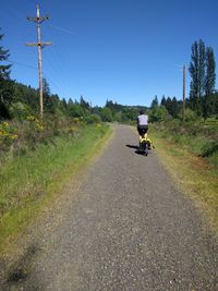 Rear view of man riding bike on road against sky