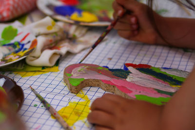 Close-up of human hand painting a wooden duck