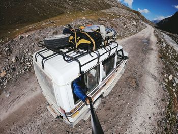 Cropped hand of man holding monopod from vehicle window on mountain