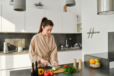 Portrait of young woman standing in kitchen