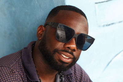 Close-up portrait of man wearing sunglasses against wall