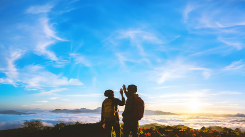 Rear view of woman standing on mountain against sky