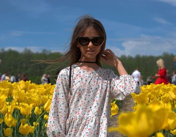 Woman wearing sunglasses standing against yellow and plants