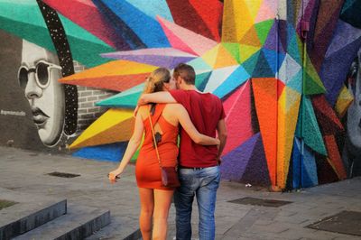 Rear view of man standing against multi colored umbrella