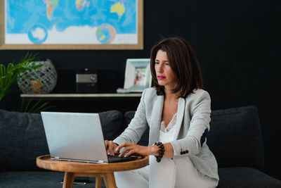 Woman using laptop while sitting on sofa at home