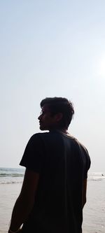 Rear view of man at beach against clear sky