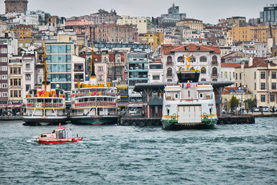 Boats sailing in sea against buildings in city