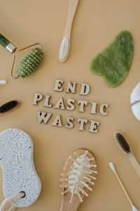 End plastic waste text around natural skin care products on neutral beige background, flat lay.