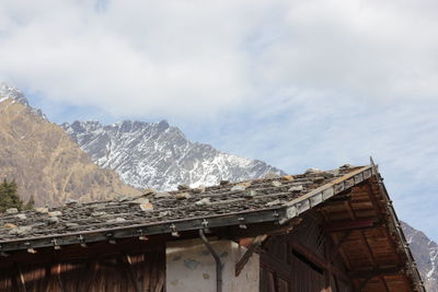 Low angle view of hut by mountains against sky