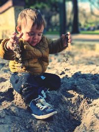 Cute toddler boy playing on sand at beach