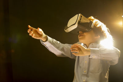 Boy wearing virtual reality simulator against black background