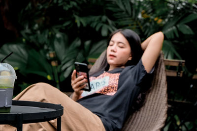 Young woman sitting on chair at park