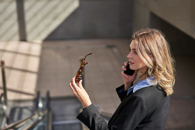 Side view of young woman standing against wall