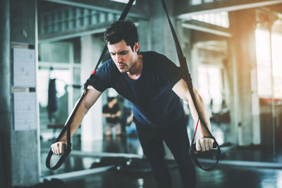 Man stretching resistance band in gym