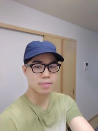 Portrait of teenage boy wearing hat against wall