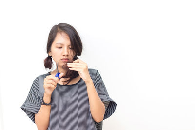 Portrait of young woman standing against white background