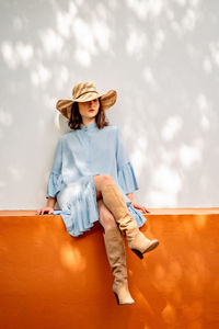 Young woman sitting in hat against sky