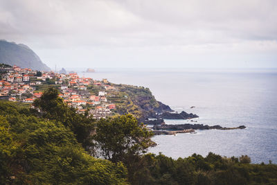 Scenic view of sea by townscape against sky