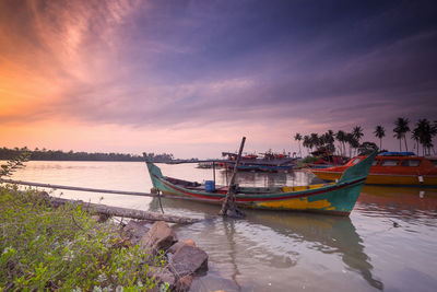 Boats moored on sea against sky during sunset