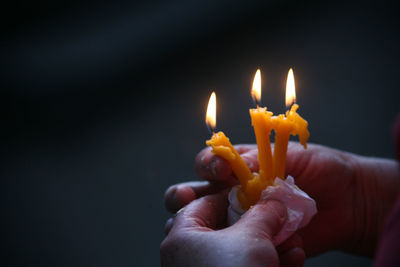 Cropped image of man holding lit candles at temple