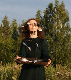 Woman playing with spoon while standing trees