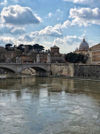 Arch bridge over river against buildings in city