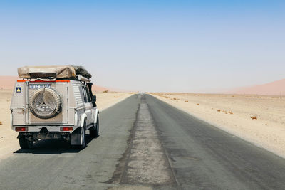 Car on desert against clear sky