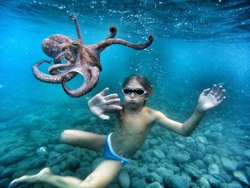 Shirtless boy touching octopus while swimming undersea