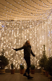 Full length of woman standing against illuminated wall