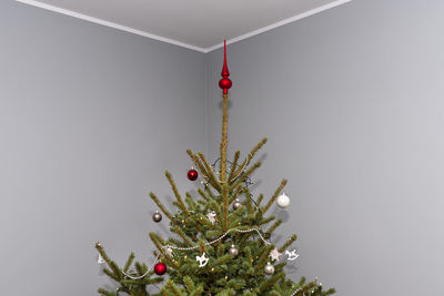 A spruce christmas tree decorated with baubles standing in the hall of a modern house.christmas tree