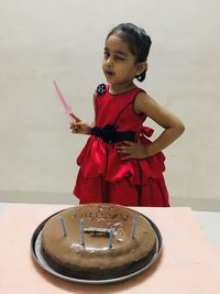 Cute girl holding ice cream standing on table