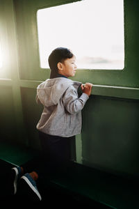 Side view of boy looking through window