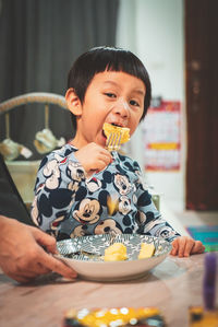 Funny face kid try to eating large piece of cake on his birthday celebrate.