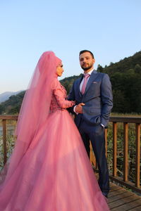 Young couple standing in park against clear sky