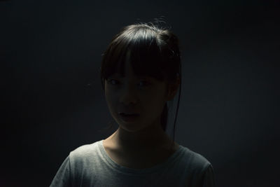 Close-up portrait of a girl over black background