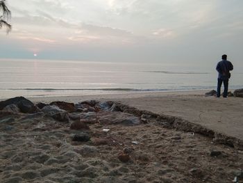 Rear view of people at beach during sunset