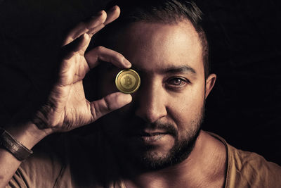 Close-up portrait of man holding black background