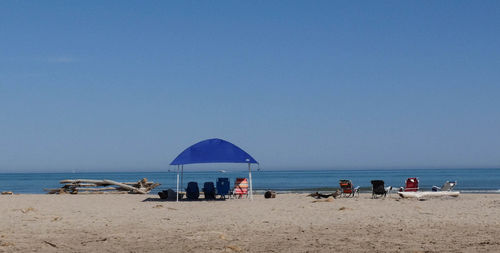 People on beach against clear blue sky