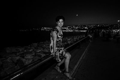 Portrait of happy young woman against illuminated sky at night