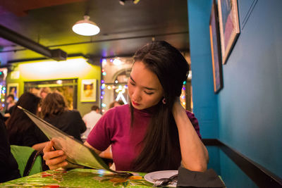 Young woman reading menu at restaurant