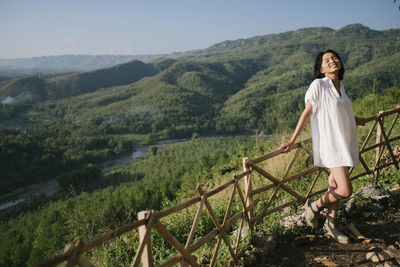 Full length of woman on railing against mountains