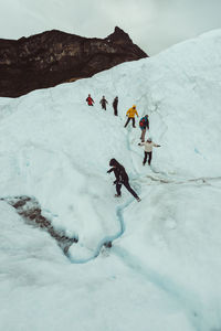 People skiing on snowcapped mountain against sky